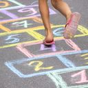 Little girl playing hopscotch outside