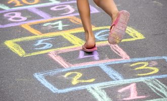 Little girl playing hopscotch outside