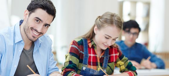 Gutt og jente som sitter i klasserommet og tar notater