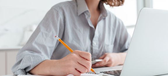 Young girl smiling taking notes by hand and on computer