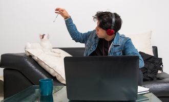 Distracted boy playing with his cat instead of doing schoolwork
