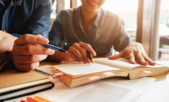 Two people reading in a book and taking notes