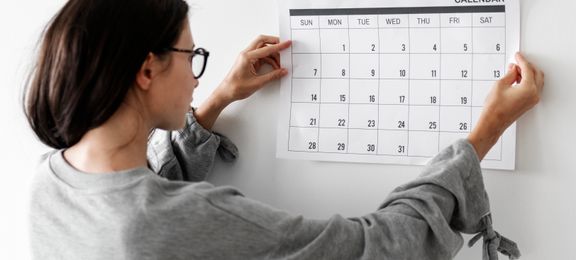 Жінка, яка тримає календар і готова планувати свій місяць